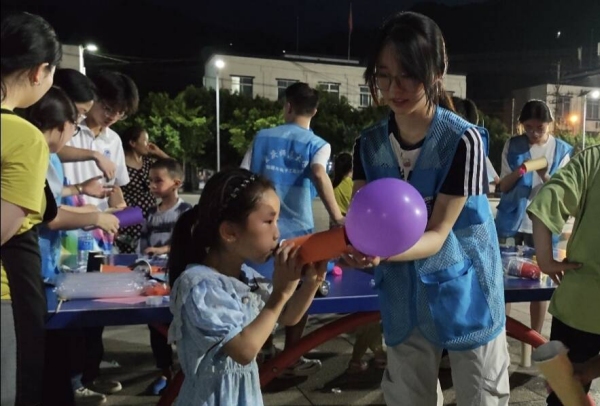 志愿者和小朋友一起体验“火箭”升空。taptap点点体育物理与电子工程学院供图