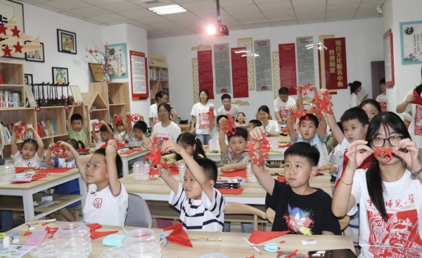 实践团成员与孩子们共同创作剪纸作品。taptap点点体育美术学院供图